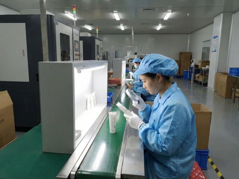 Quality control inspection of finished cosmetic tubes and bottles in a cleanroom manufacturing facility.